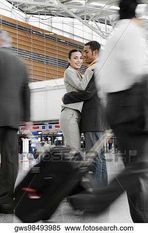 Stock Photography - Businessman and a businesswoman embracing each other at an airport. Fotosearch