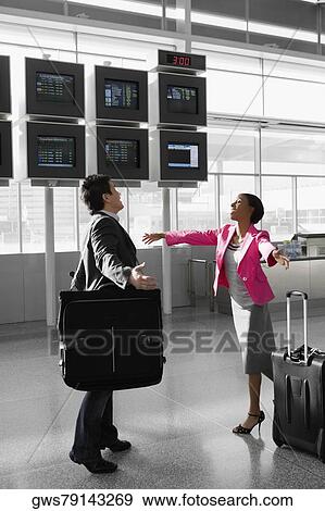 Businessman and a businesswoman walking at an airport to hug each other View Large Photo Image Stock Photo - Businessman and a businesswoman walking at an airport to hug each other. Fotosearch