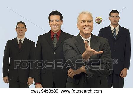 Businessman catching a rubber band ball with three businessmen standing behind him View Large Photo Image Stock Photo - Businessman catching a rubber band ball with three businessmen standing behind him. Fotosearch