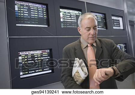 Businessman checking the time at an airport View Large Photo Image Stock Image - Businessman checking the time at an airport. Fotosearch