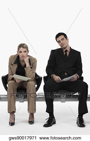 Businessman holding a file with a businesswoman sitting beside him and looking serious View Large Photo Image Stock Image - Businessman holding a file with a businesswoman sitting beside him and looking serious. Fotosearch