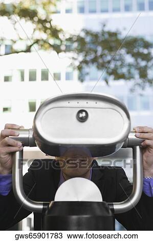 Businessman looking through a coin-operated binoculars and smiling View Large Photo Image Stock Image - Businessman looking through a coin-operated binoculars and smiling. Fotosearch