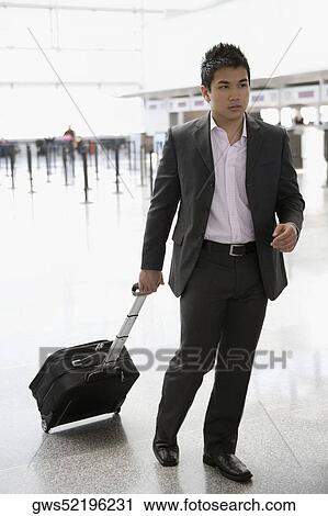 Businessman pulling his luggage at an airport View Large Photo Image Stock Image - Businessman pulling his luggage at an airport. Fotosearch