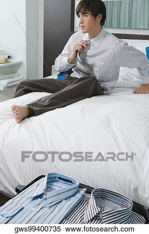 Businessman sitting on the bed and untying necktie View Large Photo Image Stock Photography - Businessman sitting on the bed and untying necktie. Fotosearch