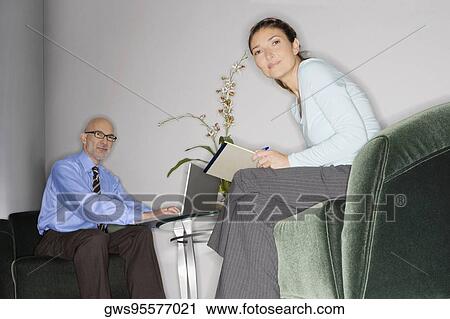 Stock Image - Businessman using a laptop with a businesswoman sitting in front of him. Fotosearch