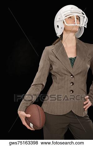 Stock Photo - Businesswoman holding an American football and thinking. Fotosearch