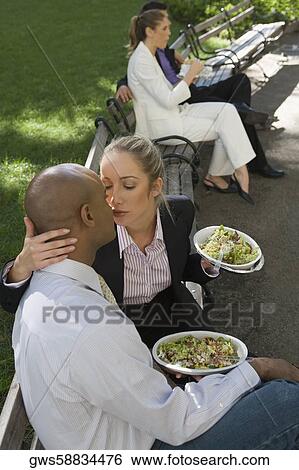 Businesswoman kissing a businessman with two business executives sitting in the background View Large Photo Image Stock Photograph - Businesswoman kissing a businessman with two business executives sitting in the background. Fotosearch