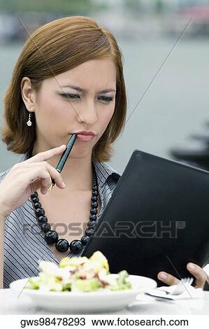 Stock Image - Businesswoman looking at a ring binder at a sidewalk cafe. Fotosearch