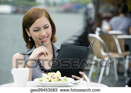 Businesswoman looking at a ring binder at a sidewalk cafe View Large Photo Image Stock Image - Businesswoman looking at a ring binder at a sidewalk cafe. Fotosearch