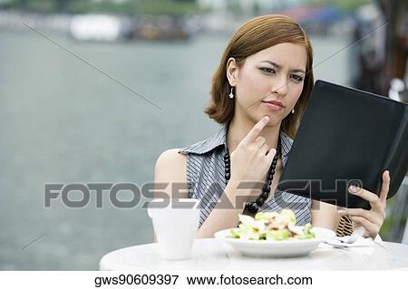 Stock Photo - Businesswoman looking at a ring binder at a sidewalk cafe. Fotosearch