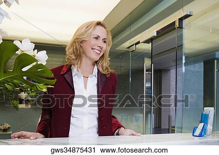 Businesswoman standing at the hotel reception and smiling View Large Photo Image Stock Image - Businesswoman standing at the hotel reception and smiling. Fotosearch