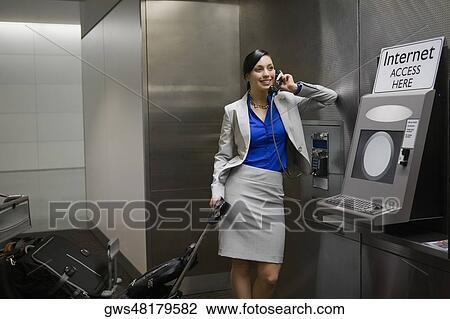 Businesswoman talking on a pay phone at an airport and smiling View Large Photo Image Stock Image - Businesswoman talking on a pay phone at an airport and smiling. Fotosearch