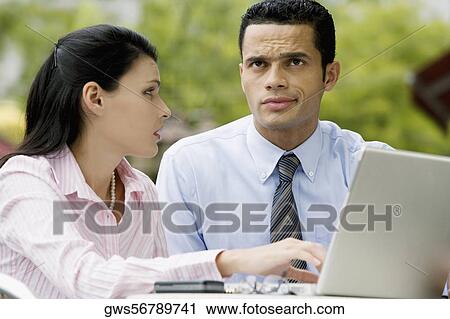 Businesswoman using a laptop with a businessman sitting beside her View Large Photo Image Stock Image - Businesswoman using a laptop with a businessman sitting beside her. Fotosearch