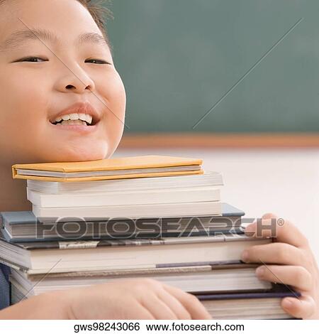 Stock Photograph - Close-up of a boy carrying books and smiling. Fotosearch