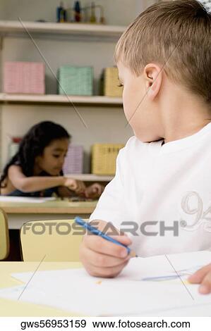 Close-up of a boy looking at a girl sitting behind him View Large Photo Image Stock Photo - Close-up of a boy looking at a girl sitting behind him. Fotosearch