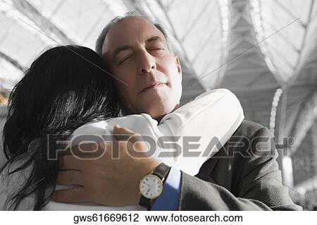 Close-up of a businessman and a businesswoman hugging each other at an airport View Large Photo Image Stock Image - Close-up of a businessman and a businesswoman hugging each other at an airport. Fotosearch