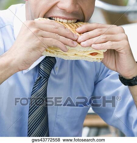 Stock Photo - Close-up of a businessman eating a cheese sandwich. Fotosearch