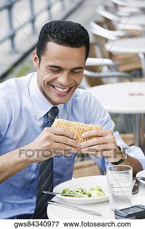 Stock Photo - Close-up of a businessman eating a cheese sandwich and smiling. Fotosearch