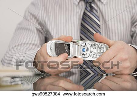 Close-up of a businessman holding a broken mobile phone View Large Photo Image Picture - Close-up of a businessman holding a broken mobile phone. Fotosearch