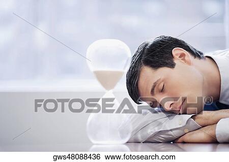 Close-up of a businessman sleeping in front of an hourglass View Large Photo Image Stock Photograph - Close-up of a businessman sleeping in front of an hourglass. Fotosearch