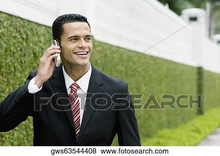 Close-up of a businessman talking on a mobile phone and smiling View Large Photo Image Stock Photo - Close-up of a businessman talking on a mobile phone and smiling. Fotosearch