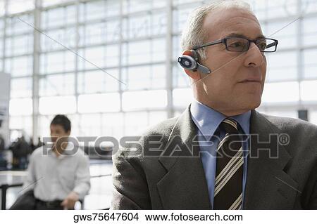Close-up of a businessman wearing a hands free device at an airport View Large Photo Image Picture - Close-up of a businessman wearing a hands free device at an airport. Fotosearch