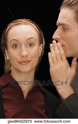 Stock Photography - Close-up of a businessman whispering into a businesswoman's ear. Fotosearch