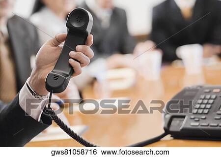 Close-up of a businessman's hand holding a telephone receiver View Large Photo Image Stock Photograph - Close-up of a businessman's hand holding a telephone receiver. Fotosearch