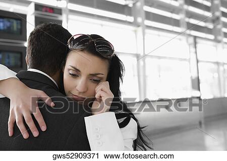 Stock Image - Close-up of a businesswoman embracing a businessman at an airport. Fotosearch
