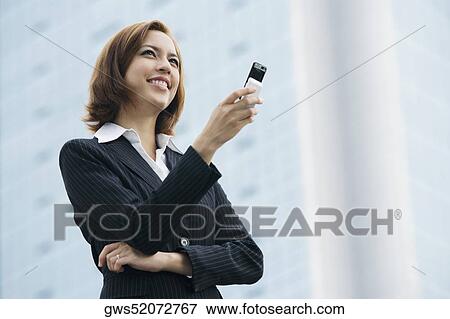 Close-up of a businesswoman holding a mobile phone and smiling View Large Photo Image Stock Photo - Close-up of a businesswoman holding a mobile phone and smiling. Fotosearch