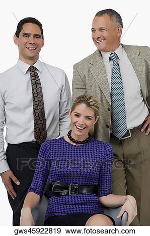 Close-up of a businesswoman smiling with two businessmen standing behind her View Large Photo Image Stock Photo - Close-up of a businesswoman smiling with two businessmen standing behind her. Fotosearch