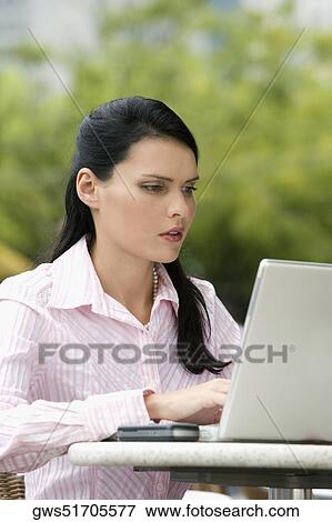 Close-up of a businesswoman using a laptop at a sidewalk cafe View Large Photo Image Stock Photo - Close-up of a businesswoman using a laptop at a sidewalk cafe. Fotosearch