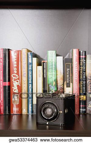 Close-up of a camera in front of books in a shelf View Large Photo Image Stock Image - Close-up of a camera in front of books in a shelf. Fotosearch
