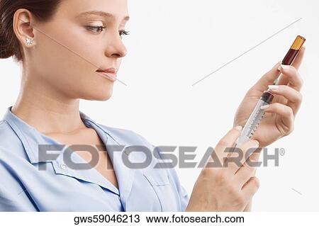 Stock Image - Close-up of a female doctor filling a syringe from a vial. Fotosearch