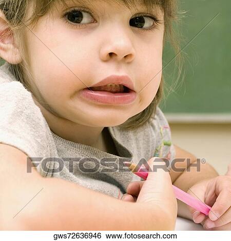 Close-up of a girl holding a colored pencil and making a face View Large Photo Image Stock Photograph - Close-up of a girl holding a colored pencil and making a face. Fotosearch
