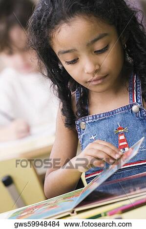 Picture - Close-up of a girl looking at a picture book. Fotosearch