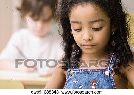 Close-up of a girl looking down with a boy sitting behind her View Large Photo Image Stock Photo - Close-up of a girl looking down with a boy sitting behind her. Fotosearch