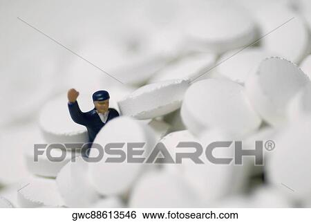 Stock Photograph - Close-up of a human figurine on the heap of pills. Fotosearch