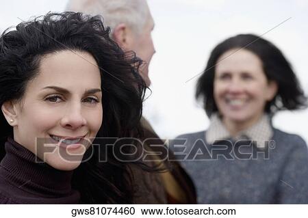 Close-up of a mature woman with a couple behind her View Large Photo Image Stock Image - Close-up of a mature woman with a couple behind her. Fotosearch