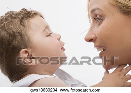 Close-up of a mid adult woman looking at her son and smiling View Large Photo Image Picture - Close-up of a mid adult woman looking at her son and smiling. Fotosearch