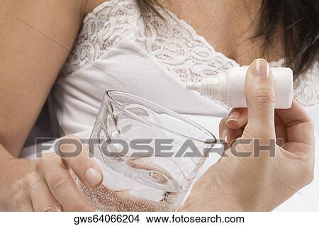 Close-up of a person's hand dropping medicine into a glass of water View Large Photo Image Picture - Close-up of a person's hand dropping medicine into a glass of water. Fotosearch