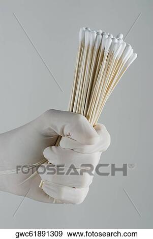 Stock Photo - Close-up of a person's hand holding cotton swabs. Fotosearch