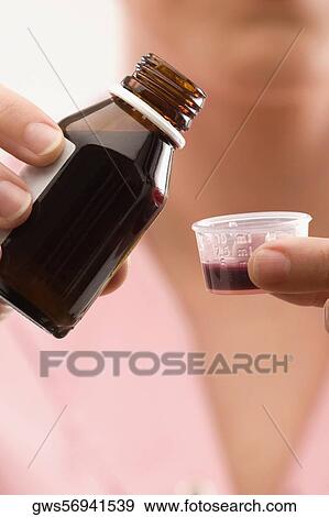 Close-up of a person's hand pouring syrup into a bottle cap View Large Photo Image Stock Photo - Close-up of a person's hand pouring syrup into a bottle cap. Fotosearch