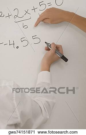 Stock Image - Close-up of a person's hand solving mathematical problem on a white board. Fotosearch