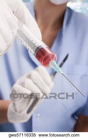 Stock Photography - Close-up of a surgeon holding a syringe. Fotosearch