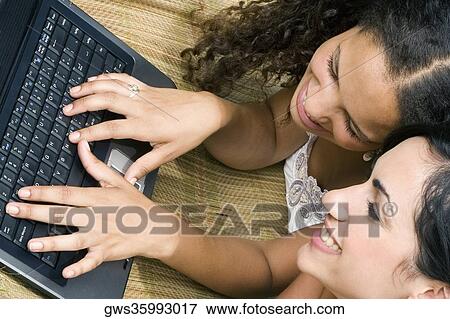 Close-up of a teenage girl using a laptop with her friend and smiling View Large Photo Image Stock Photo - Close-up of a teenage girl using a laptop with her friend and smiling. Fotosearch