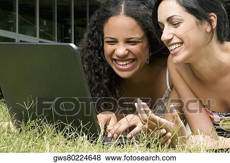 Close-up of a teenage girl using a laptop with her friend and smiling View Large Photo Image Stock Photo - Close-up of a teenage girl using a laptop with her friend and smiling. Fotosearch