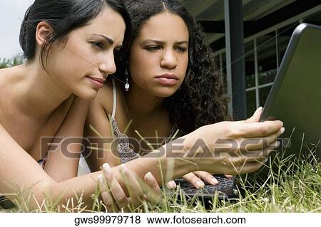Close-up of a teenage girl using a laptop with her friend View Large Photo Image Stock Photo - Close-up of a teenage girl using a laptop with her friend. Fotosearch