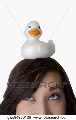 Close-up of a young woman balancing a toy duck on her head View Large Photo Image Stock Photo - Close-up of a young woman balancing a toy duck on her head. Fotosearch