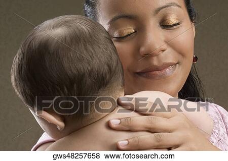 Close-up of a young woman carrying her son and smiling View Large Photo Image Stock Photo - Close-up of a young woman carrying her son and smiling. Fotosearch
